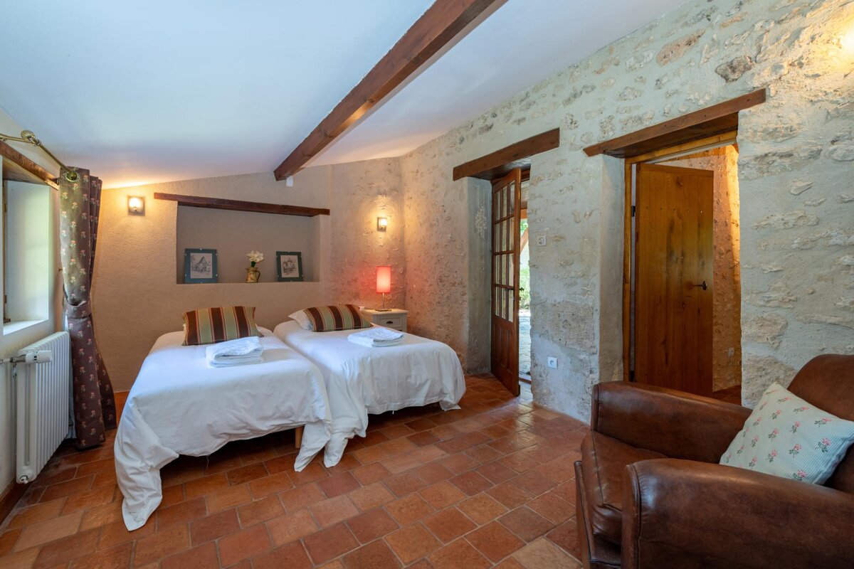 A bedroom with two twin beds and a chair