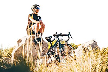 A woman sits on a rock next to her bike