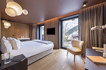 A hotel room with a large bed and a chair