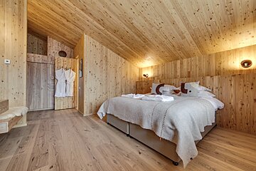 A bedroom with a wooden ceiling and a bed
