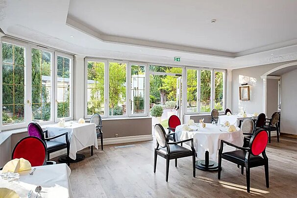A dining room with tables and chairs and a green exit sign
