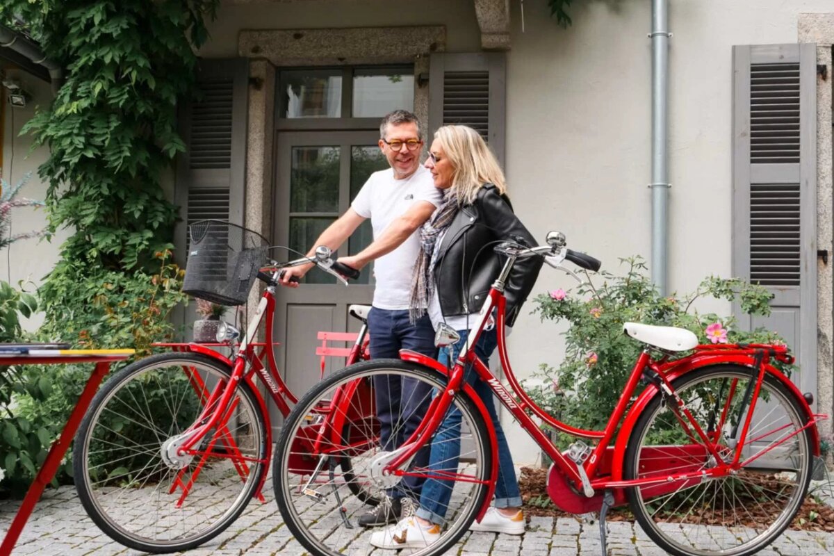 A man and woman are standing next to a red bicycle that says ' holland ' on it