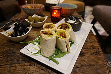 starters of olives and wraps on a white plate
