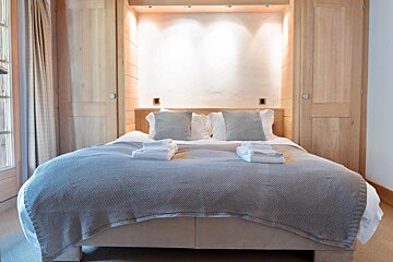 A bed with a grey blanket and pillows in a bedroom