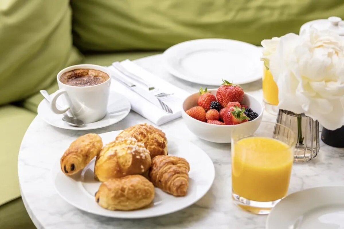 A table with a bowl of fruit and a cup of coffee
