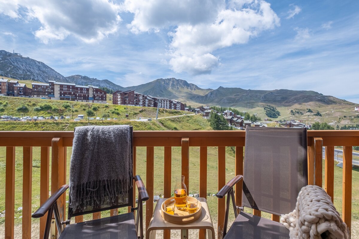 A balcony with two chairs and a bottle of orange juice