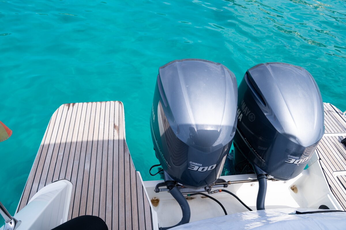 Two Yamaha 300 outboard engines and a wooden boat deck over clear turquoise water.
