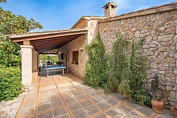 A stone house with a ping pong table on the patio