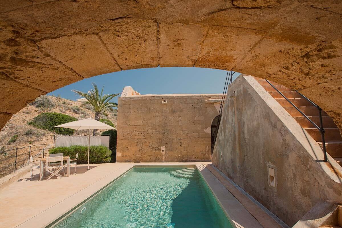 A swimming pool is under a stone archway