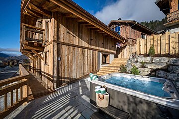 A hot tub sits outside of a wooden building