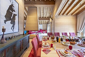 A dining room with a large painting on the wall above the table
