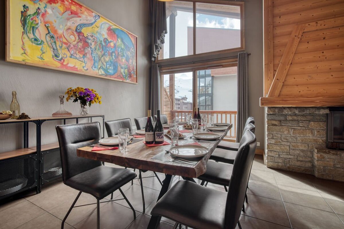 A dining room table with a bottle of wine on it