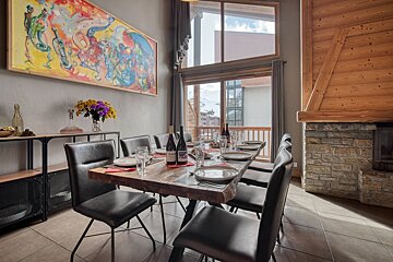 A dining room table with a bottle of wine on it