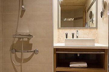 A bathroom with a sink , mirror and shower