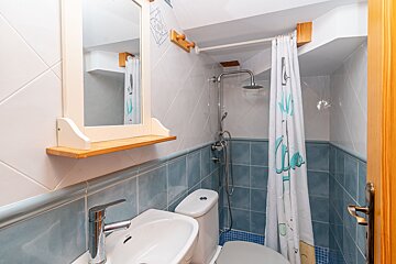 A bathroom with blue tiles and a shower curtain that says