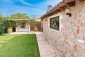 A stone building with a barbecue area in the backyard
