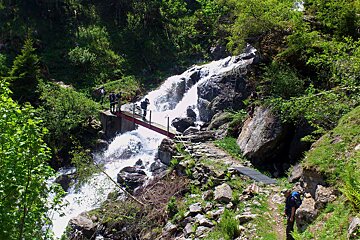 An image of a bridge across a waterfall in the mountains with hikers near Chamonix Mont Blanc