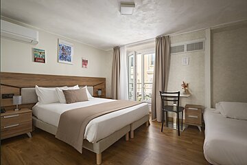 A hotel room with a large bed and two smaller beds