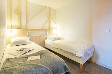 A small bedroom with two beds and a book on the bed