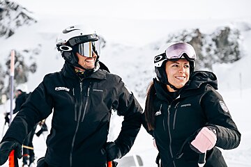 A man wearing a patagonia jacket stands next to a woman