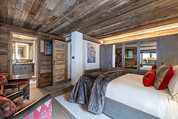 A bedroom with a large bed and a chair