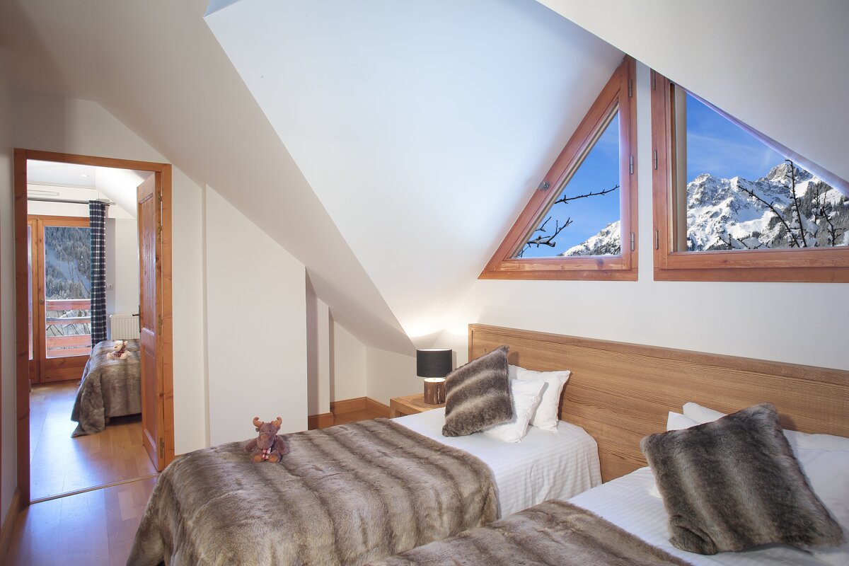 A bedroom with two beds and a window with mountains in the background