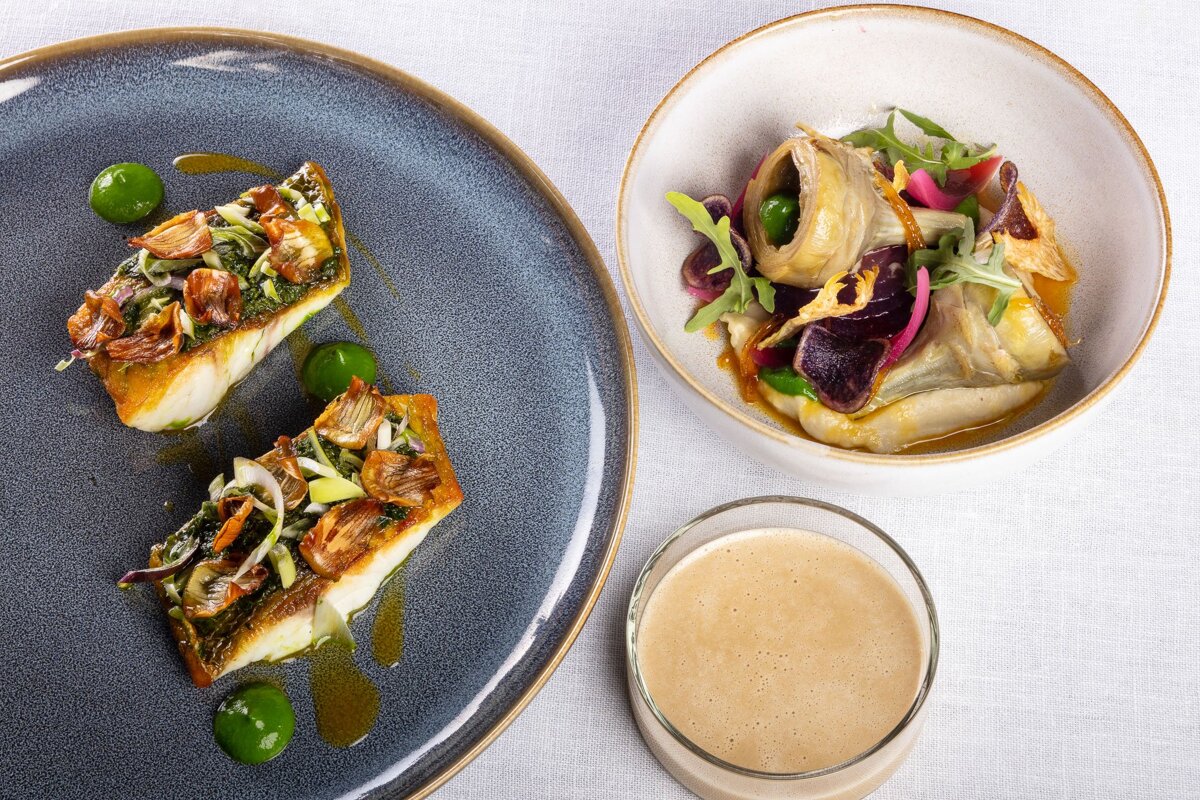 A plate of food next to a bowl of food and a glass of liquid