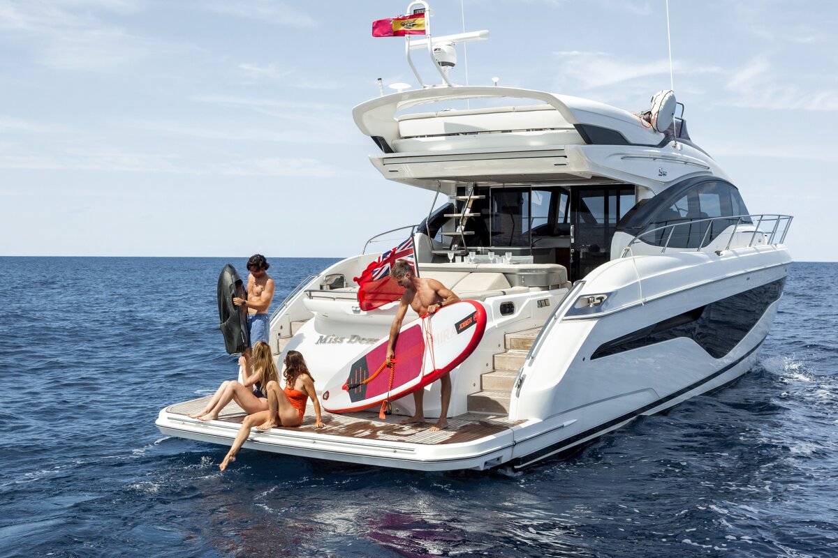 A group of people on a yacht with the name miss dew on the back