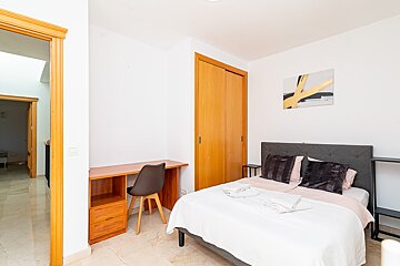 A bedroom with a bed a desk and a chair