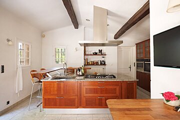 A kitchen with wooden cabinets and a flat screen tv