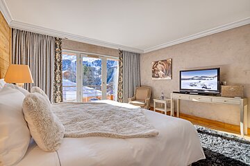 A bedroom with a large bed and a flat screen tv