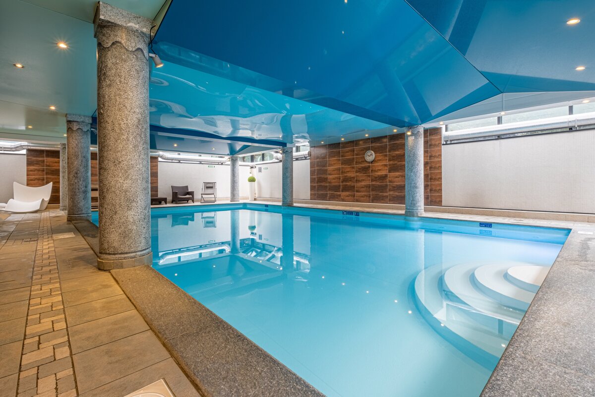 A large indoor swimming pool with a blue ceiling
