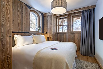 A bedroom with a large bed and two windows