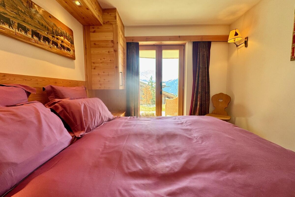 A bedroom with a purple bed and a picture of cows on the wall