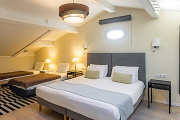 A hotel room with three beds and a round window