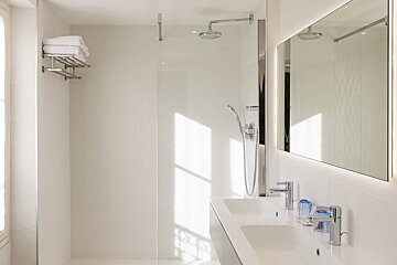 A bathroom with two sinks and a walk in shower