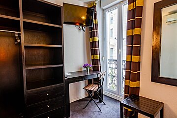 A room with a desk a chair and a television