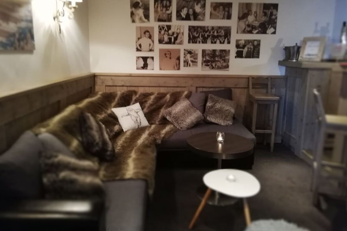 A room with a couch and a table with pictures on the wall