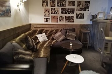 A room with a couch and a table with pictures on the wall