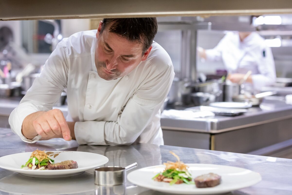 A chef prepares a plate of food in a kitchen