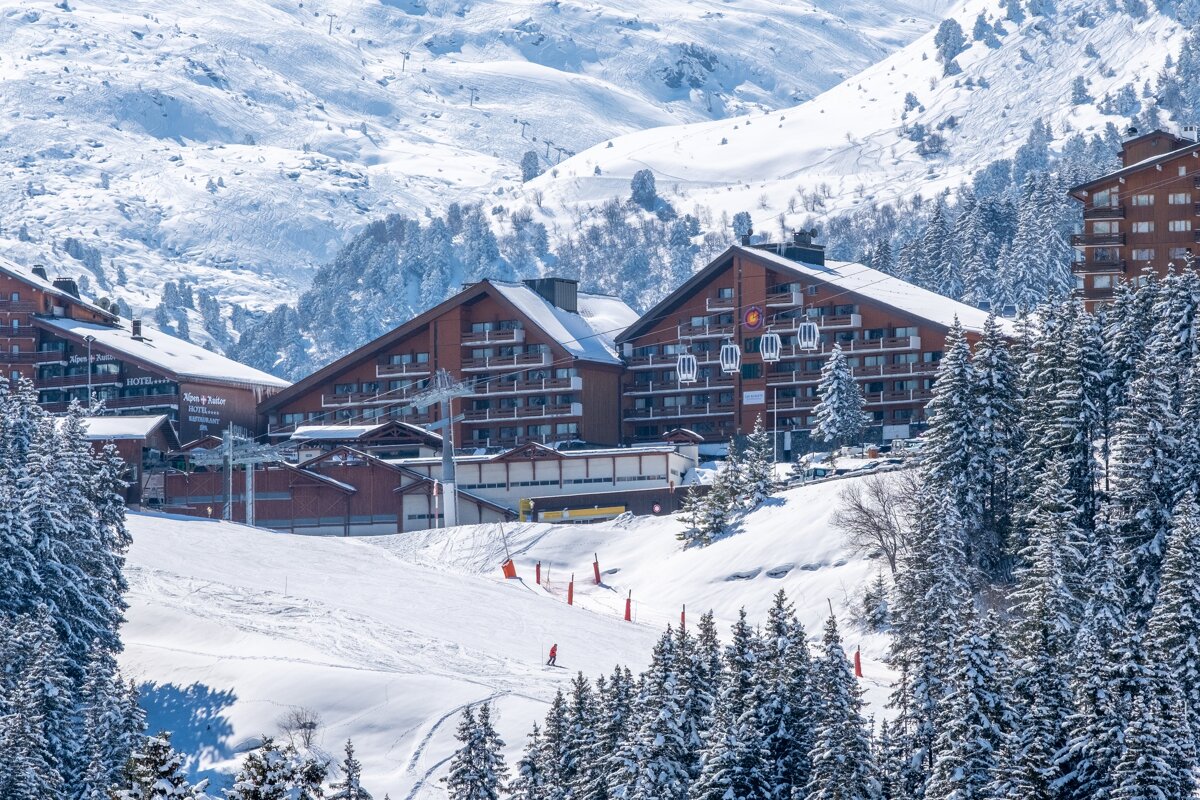 A ski resort is surrounded by snow covered trees and mountains