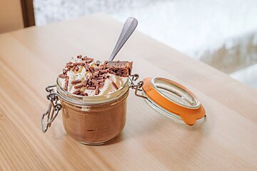 A jar of chocolate mousse with whipped cream and chocolate shavings