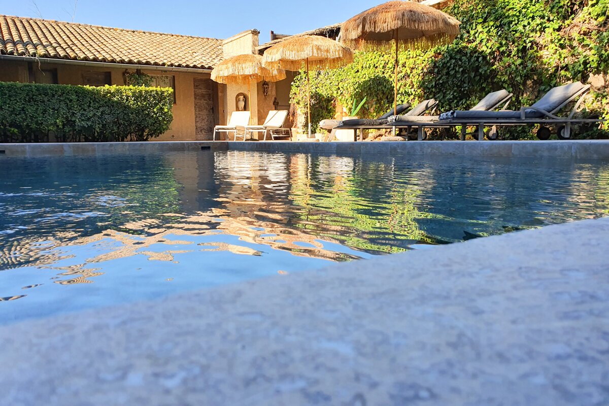 A swimming pool with chairs and umbrellas around it