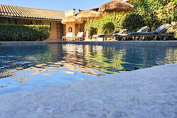 A swimming pool with chairs and umbrellas around it
