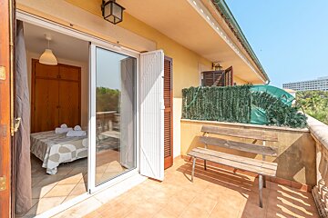 A balcony with a wooden bench and a bed