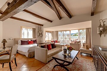 A hotel room with a couch and a bottle of wine