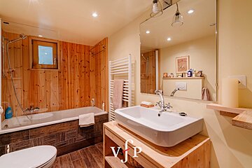 A bathroom with wooden walls and a sink and toilet