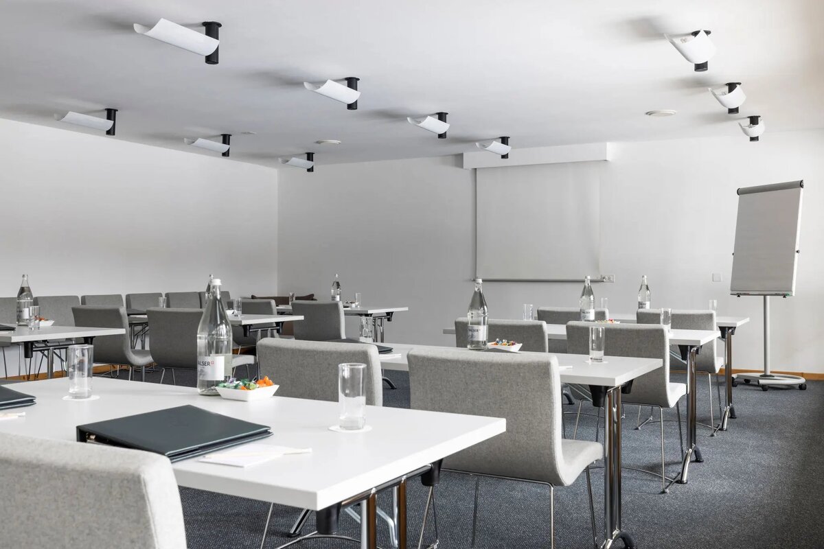 A conference room with tables and chairs and bottles of water