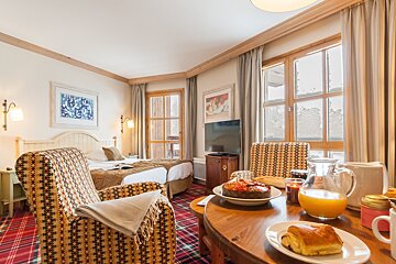 A hotel room with two beds and a table with a plate of food on it