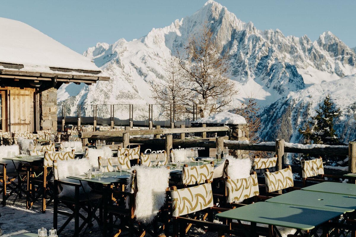 A row of tables and chairs in front of a snowy mountain